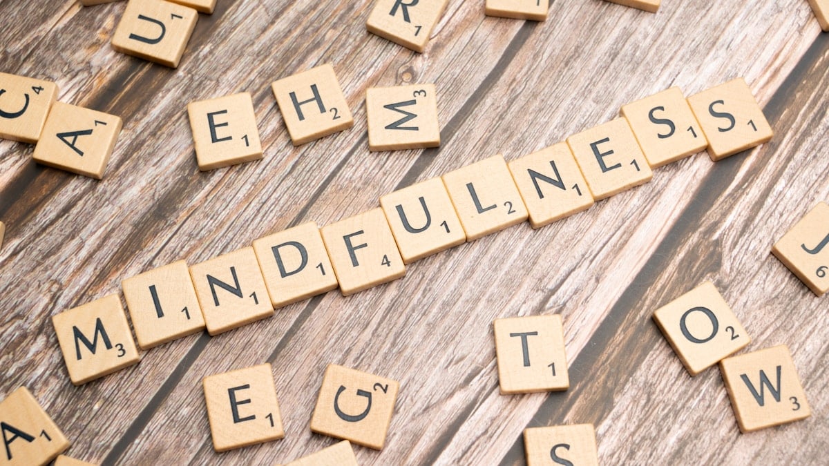 scrabble tiles spelling the word mindfulness on a wooden surface